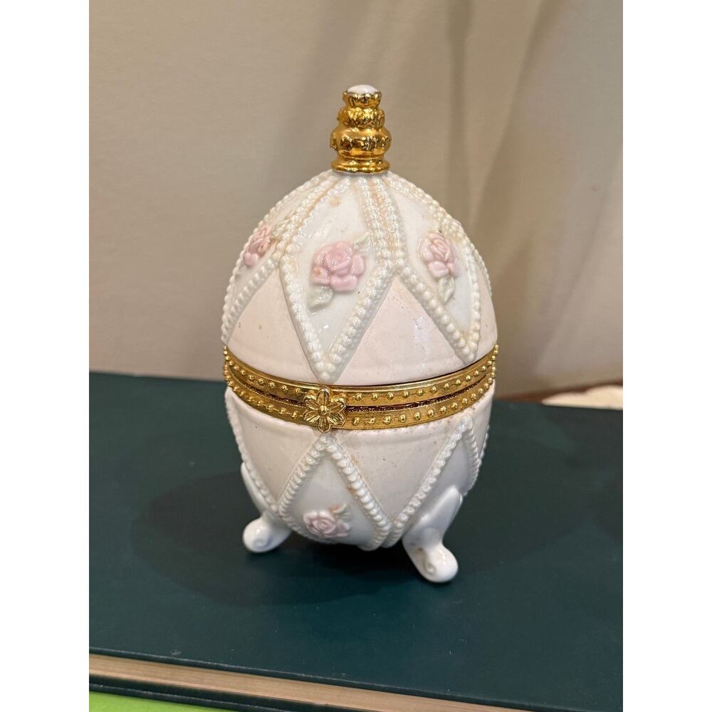 white and pink porcelain egg-shaped trinket box gold trim and a hinged lid